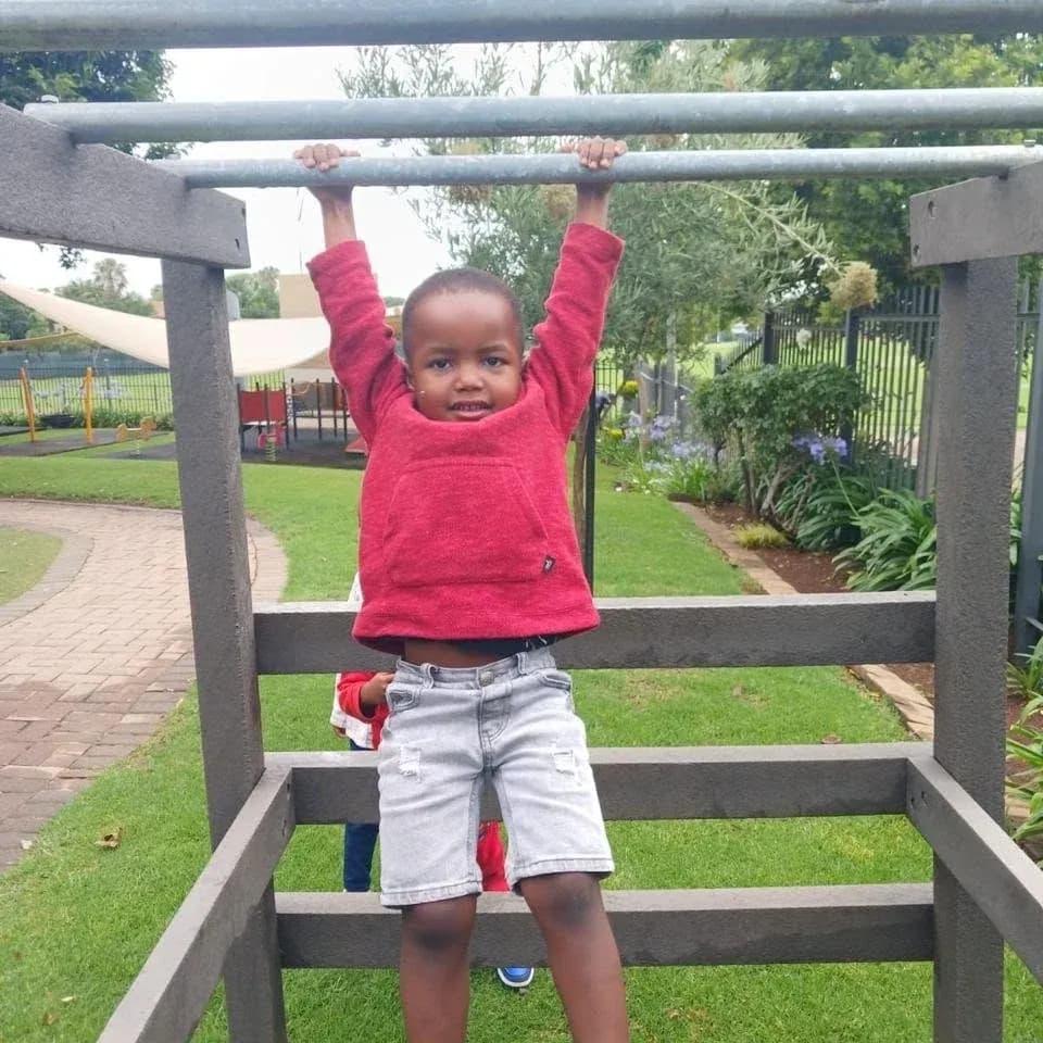 Curro Hazeldean preschool learner hanging from monkey bars during an Out of the Blocks activity